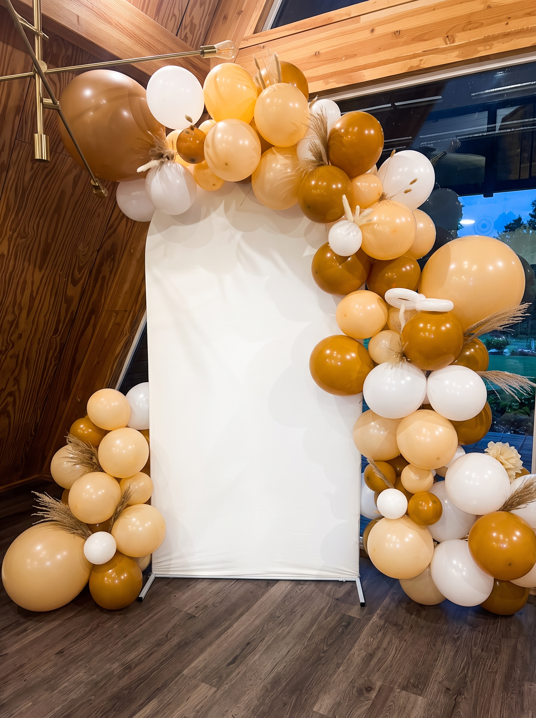 Boho caramel, tan and white balloon garland with pampas grass on an arch backdrop